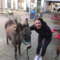 Frau mit einem Esel vor der Terrasse des Café Bistro Picasso.