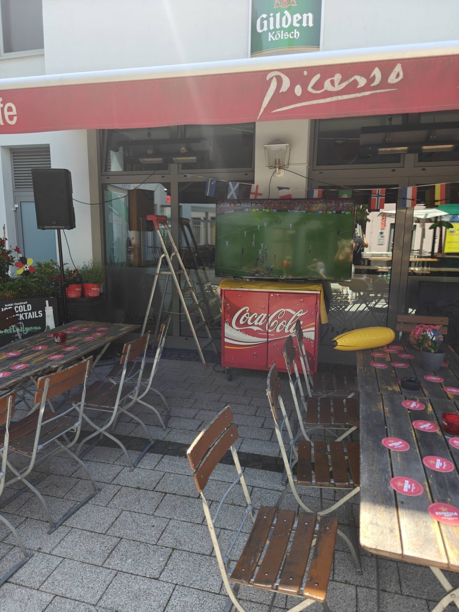 Fußballübertragung auf der Picasso-Terrasse mit Deutschland-Dekoration und Coca-Cola-Kühlschrank.