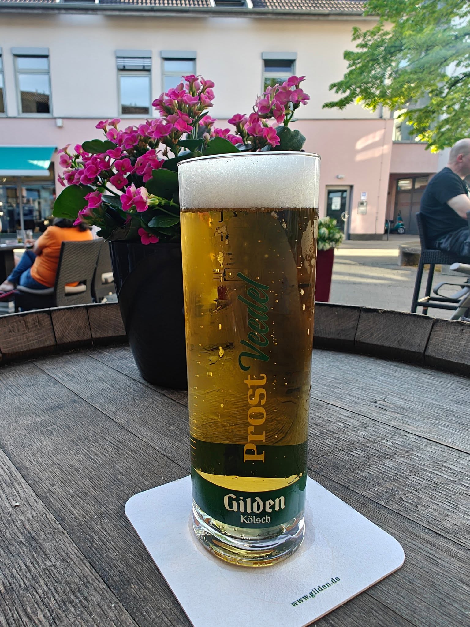 Ein Veltins-Bierglas mit Blumen auf einem Tisch der Picasso-Terrasse.